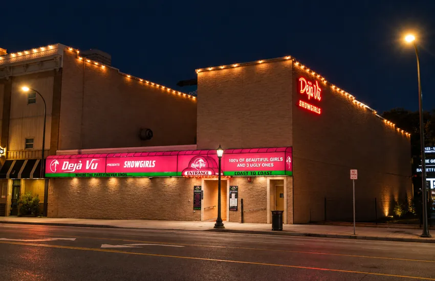 Déjà Vu Showgirls at night — neon sign, awning, and entrance on Washington Ave, Minneapolis