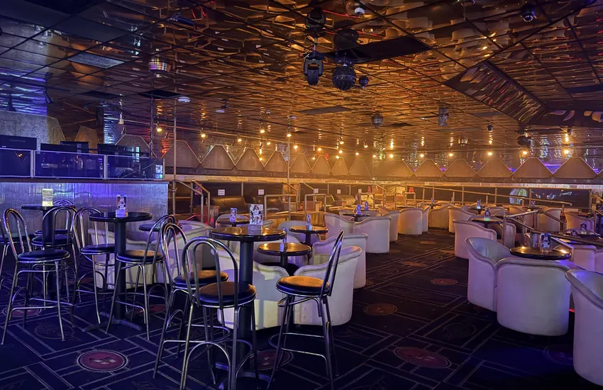 The main room at Déjà Vu Minneapolis — lounge chairs and tables under the mirrored gold ceiling