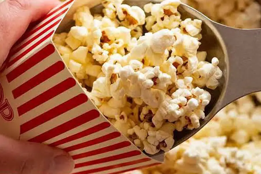Fresh popcorn scooped into a striped box — free every night at Déjà Vu Minneapolis
