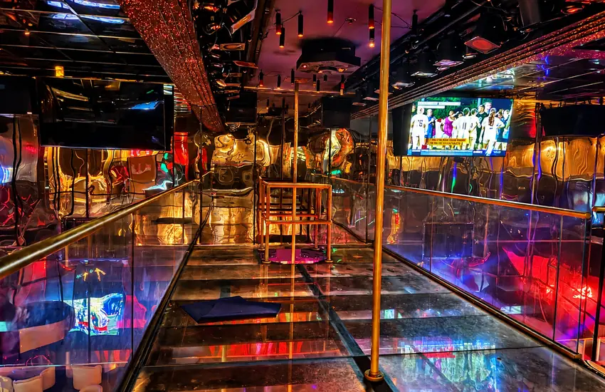 The mirrored upstairs catwalk with brass rails and poles