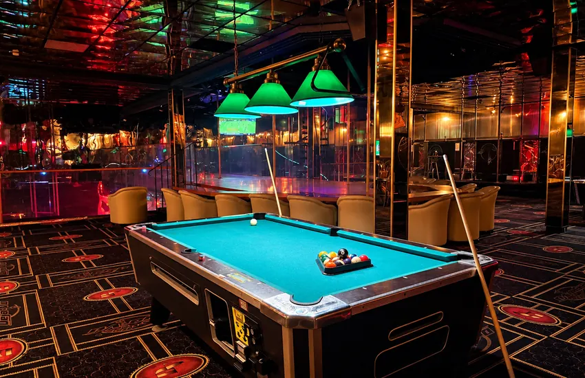 Pool table under green lamps overlooking the stage below